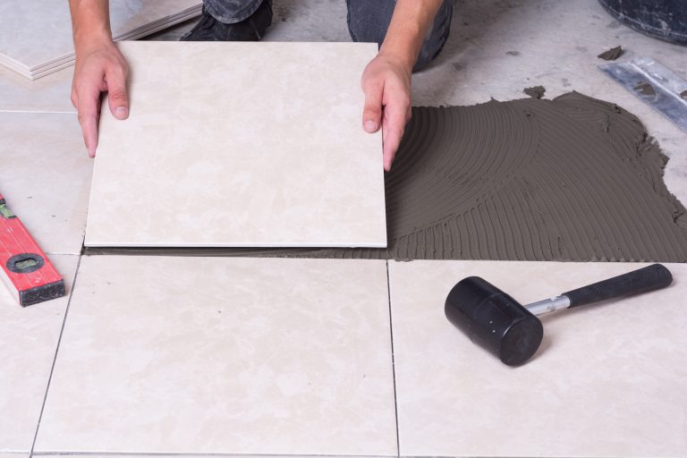 Tiler installing ceramic tiles on a floor .